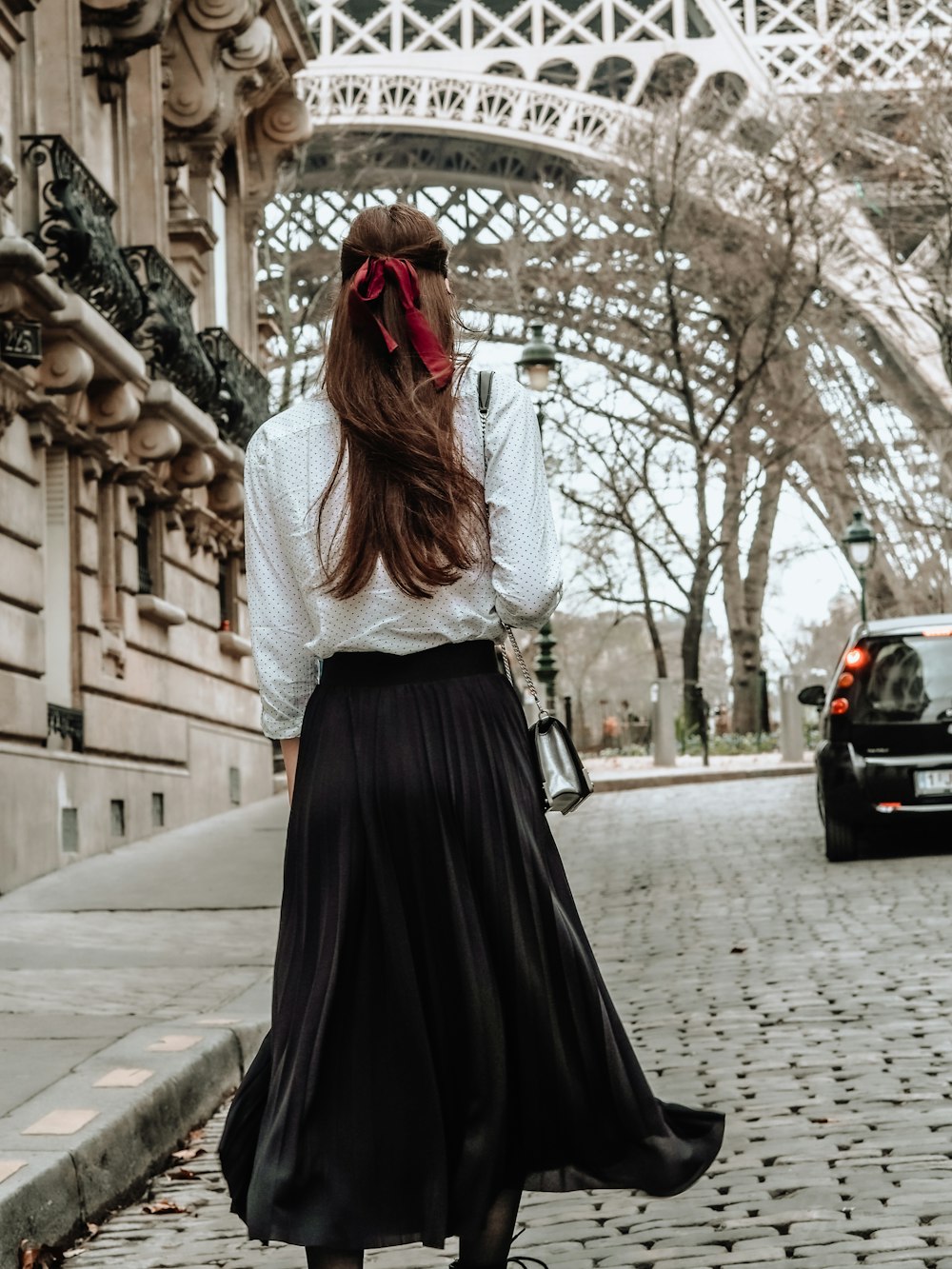 donna in abito a maniche lunghe bianco e nero in piedi sul marciapiede durante il giorno