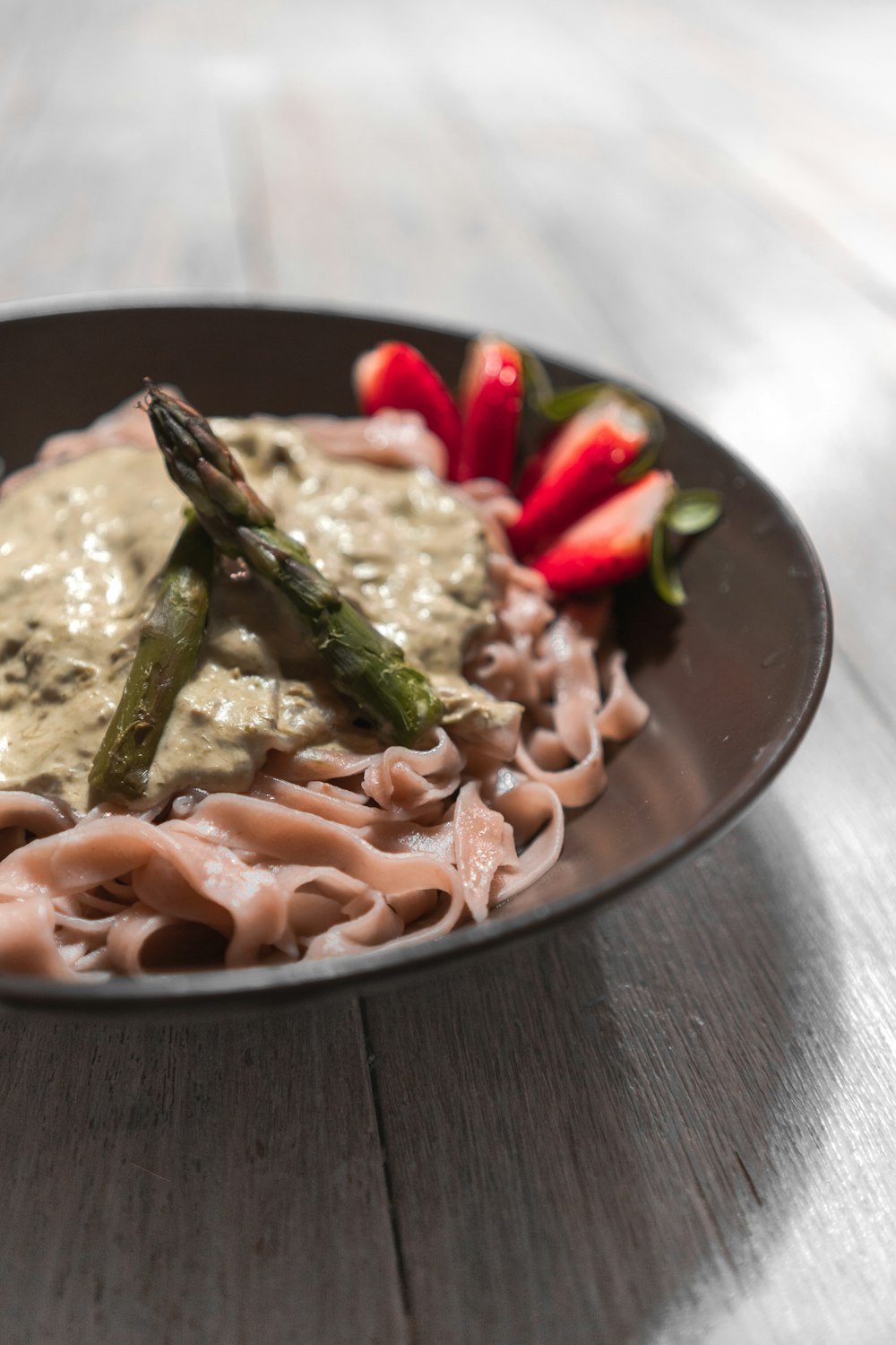 pasta with sliced tomato and green leaf vegetable on round ceramic plate