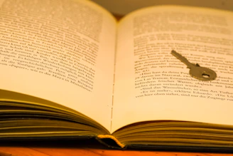 An old key resting atop an open book symbolizing knowledge unlocking.