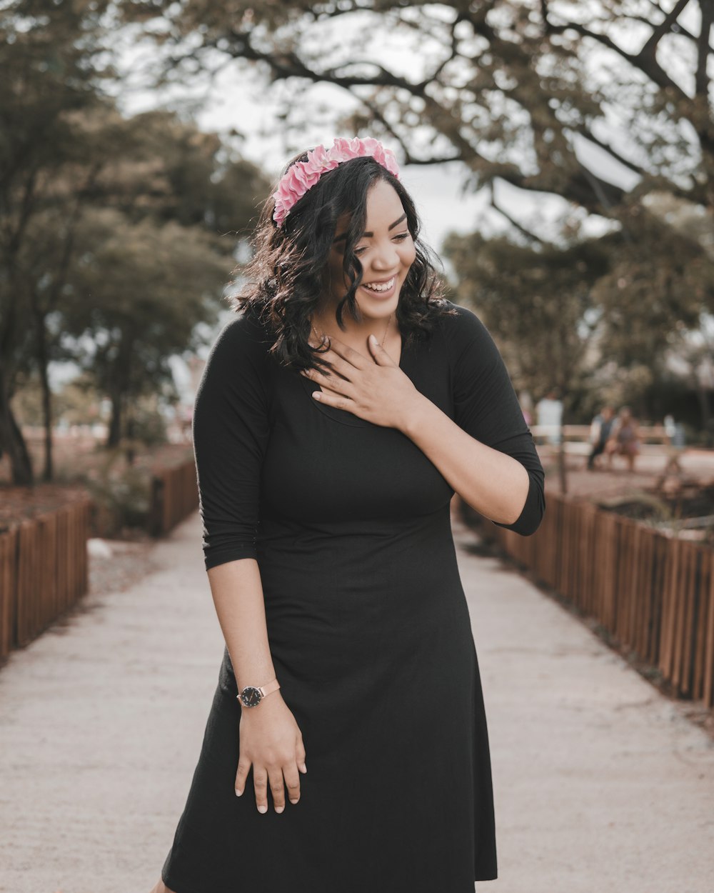 woman in black long sleeve dress standing on gray concrete pathway during daytime