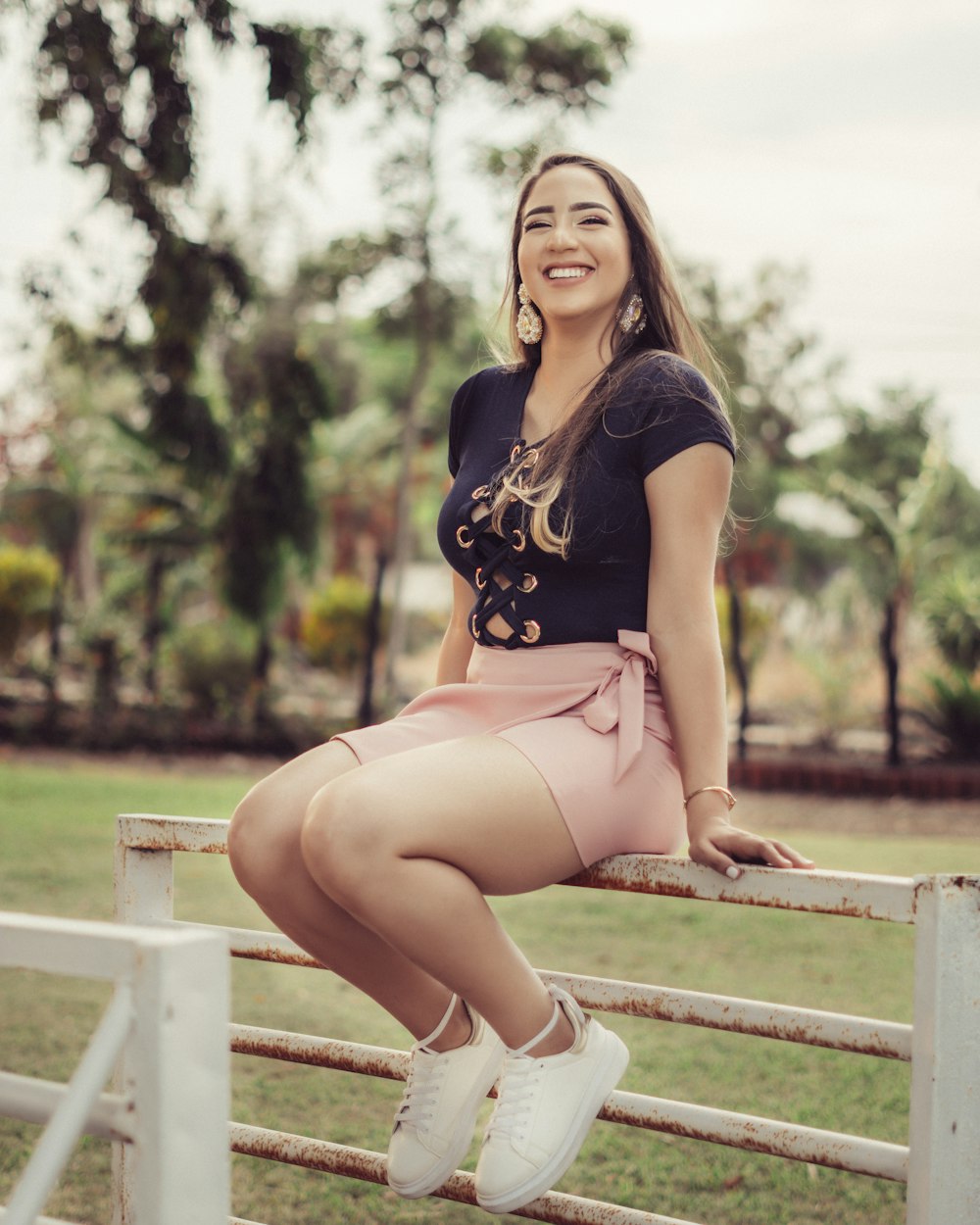 woman in black and yellow floral dress sitting on white wooden fence during daytime