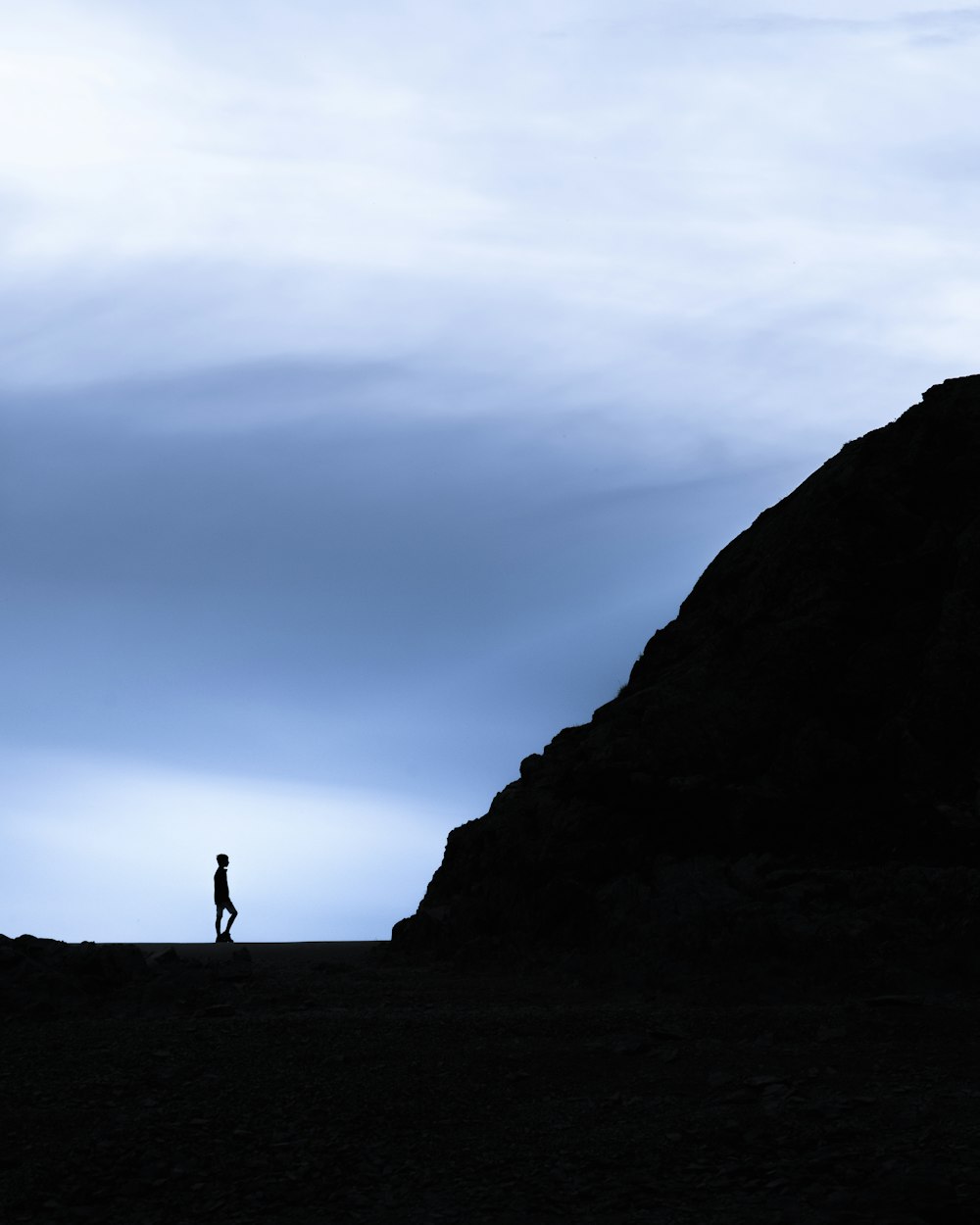 silhouette of person standing on rock formation during daytime