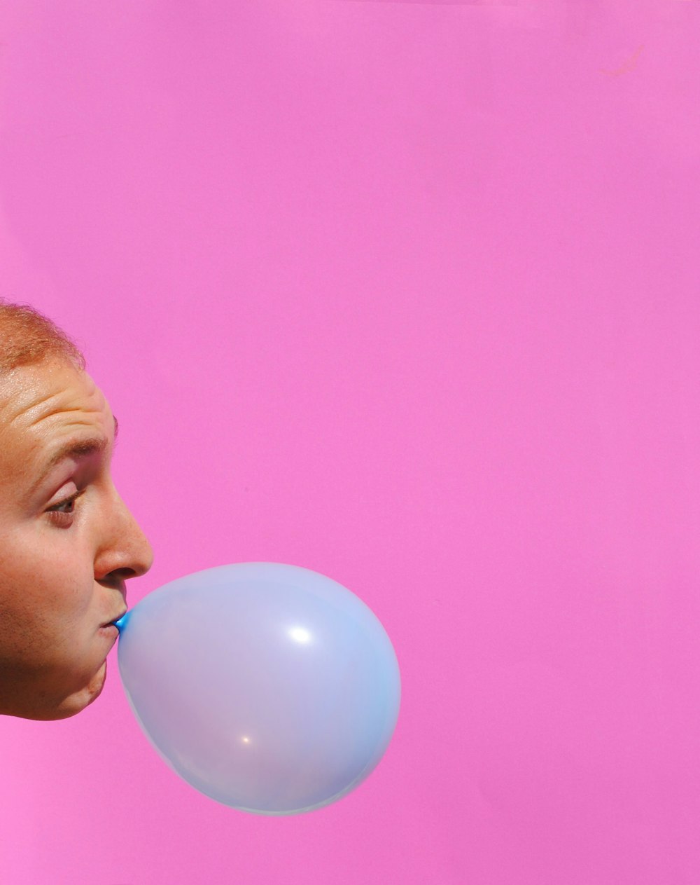Mujer con globo azul en la boca