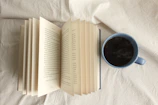 Close-up of an open book with a steaming cup of coffee nearby