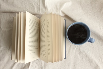 An open book with notes and a cup of coffee beside it.