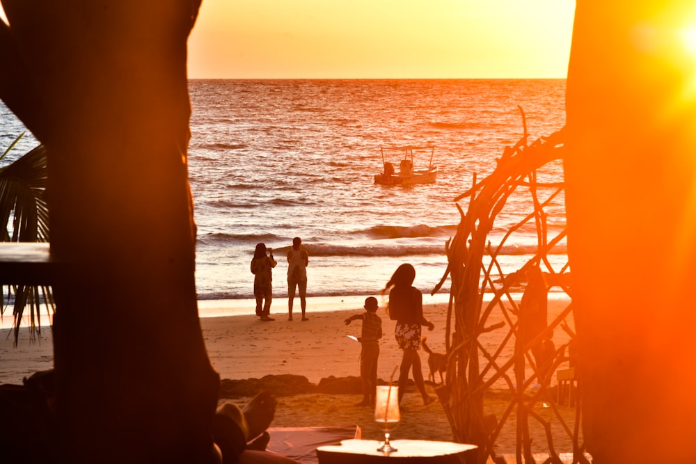 Silueta de la gente en la playa durante la puesta del sol