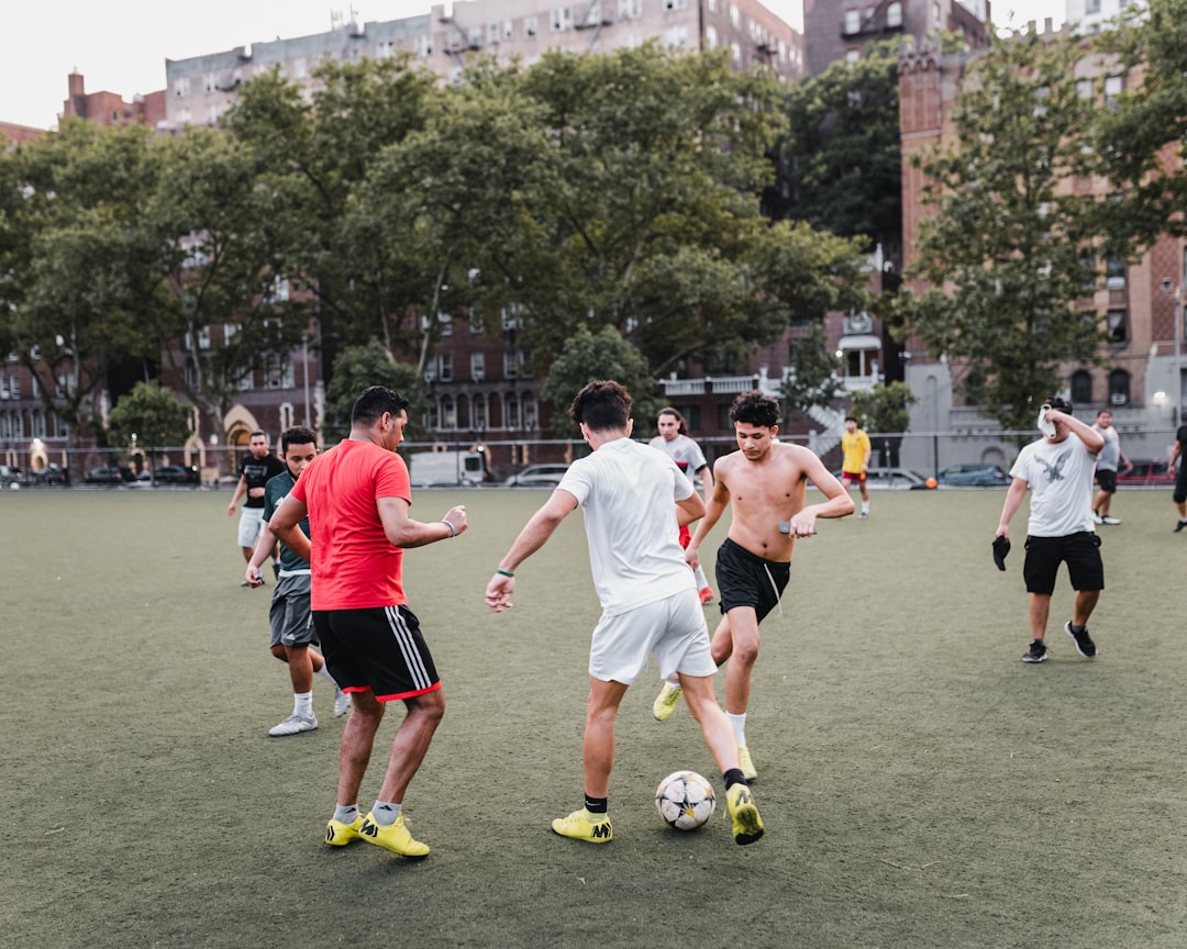 group of people playing soccer on green grass field during daytime
