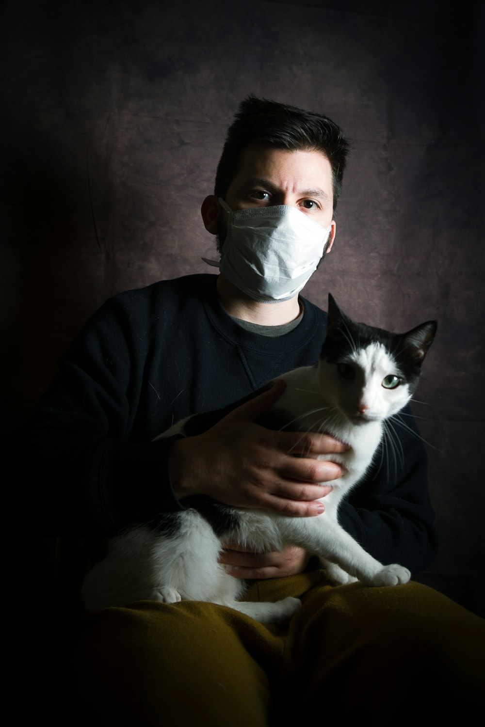 man in black long sleeve shirt holding white and black cat