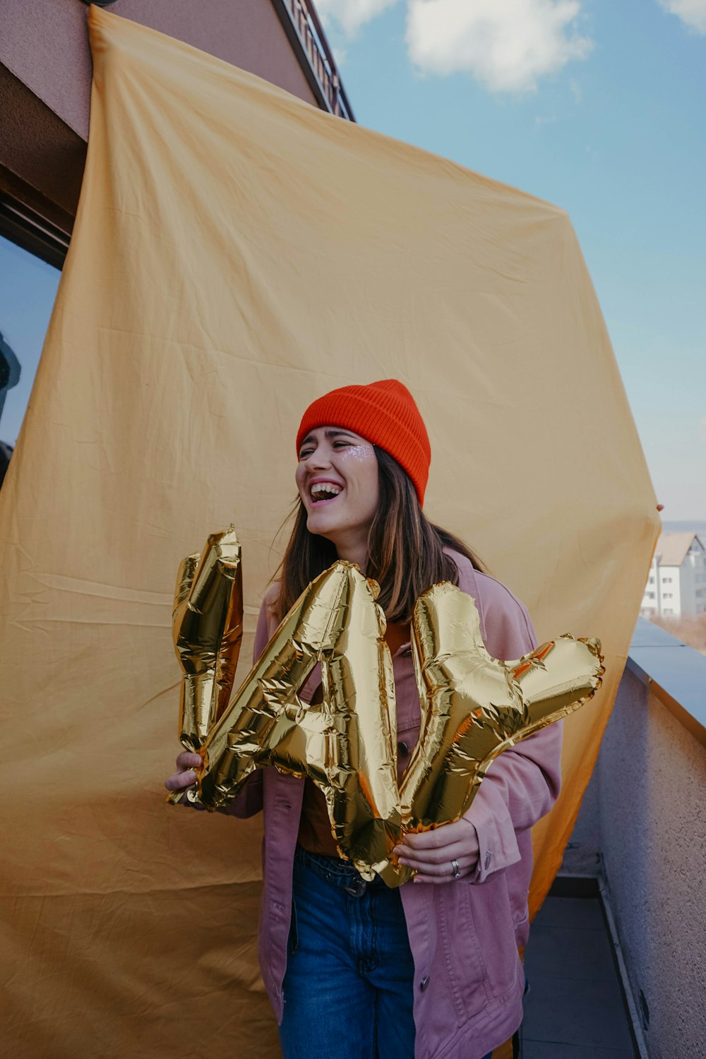 Femme en bonnet en tricot rouge et manteau marron tenant un trophée d’or