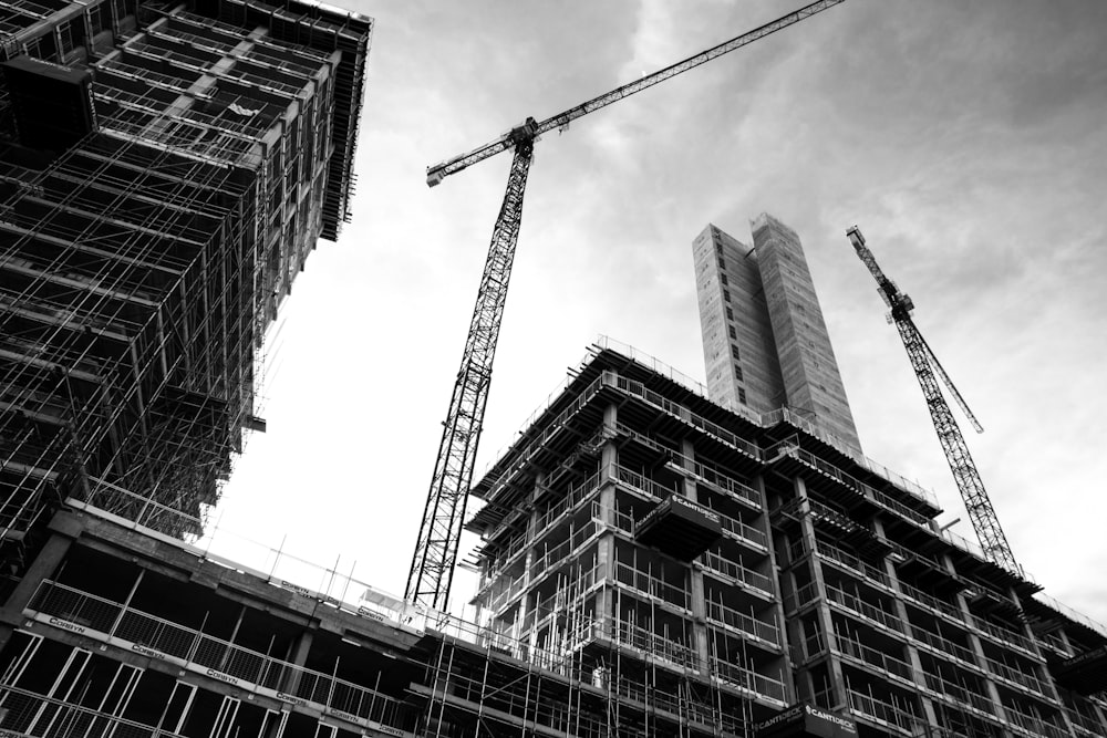 grayscale photo of crane in front of building