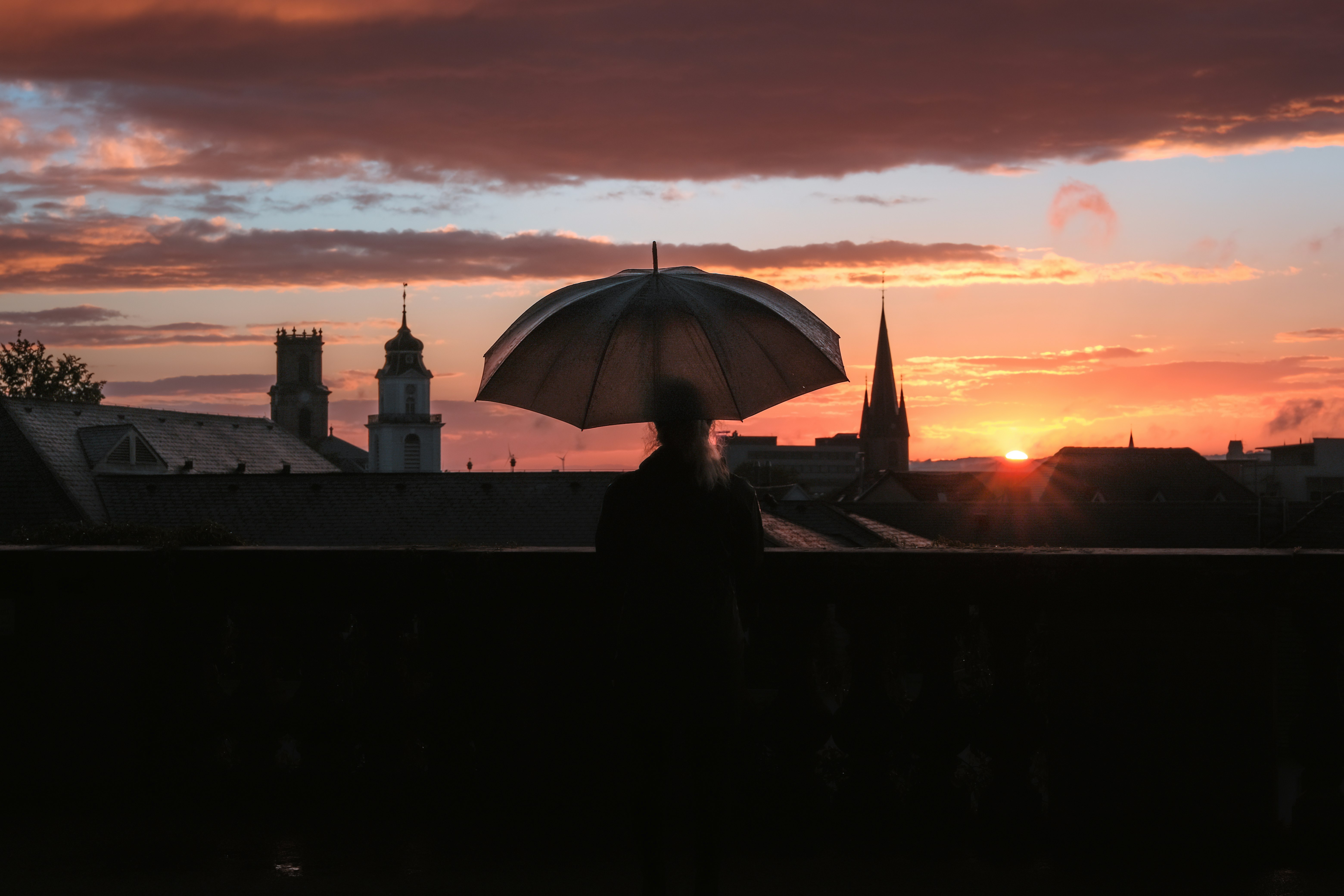 silhouette of person under umbrella during sunset
