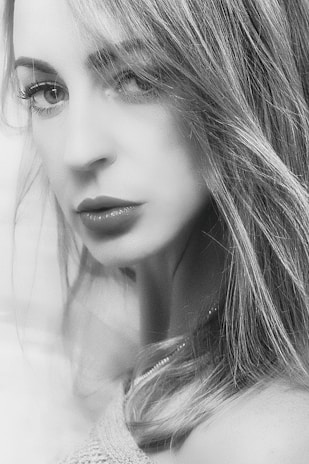 Black and white portrait of a young woman with intense eyes and soft lighting.
