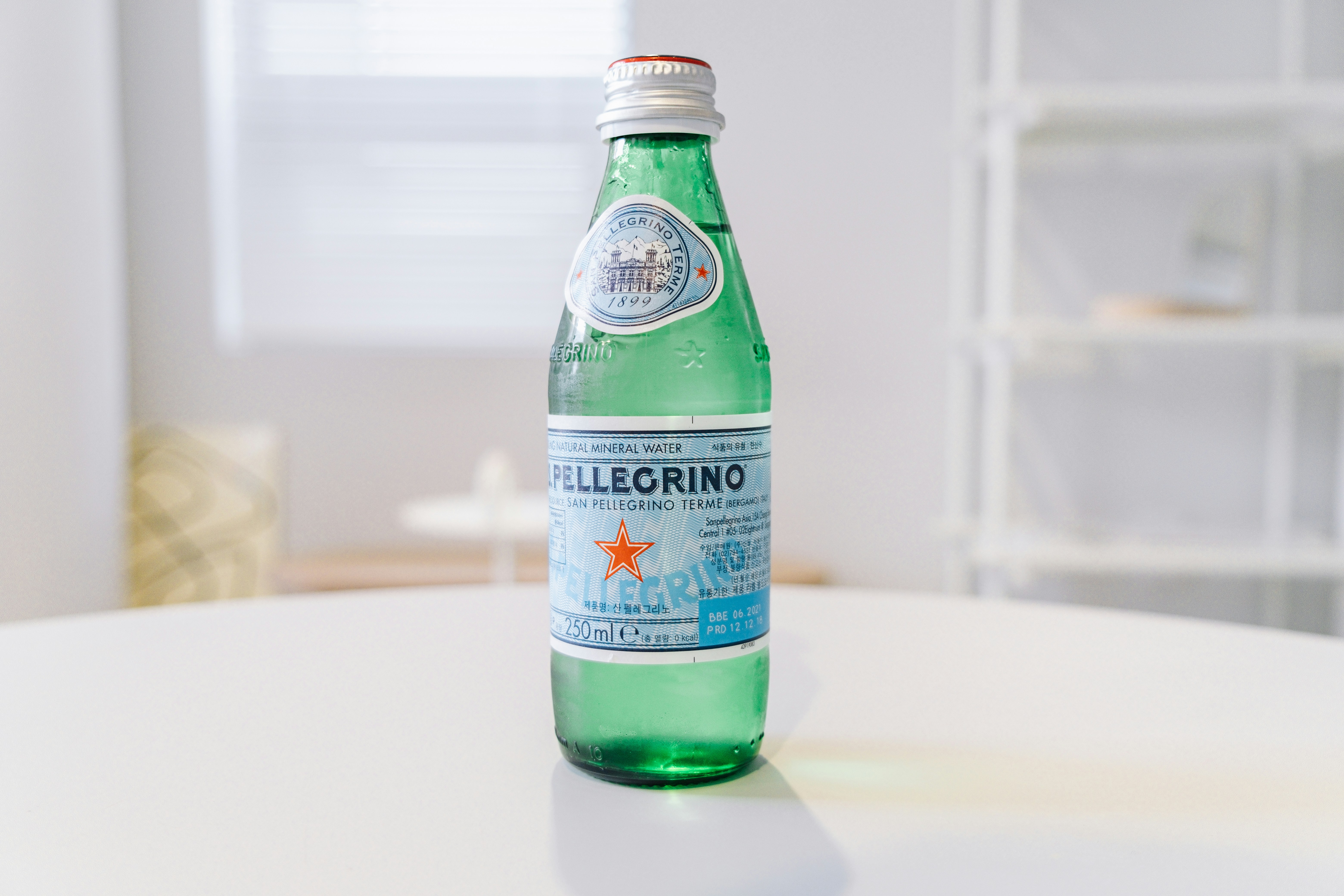 S.Pellegrino bottle covered in condensation on a white table.