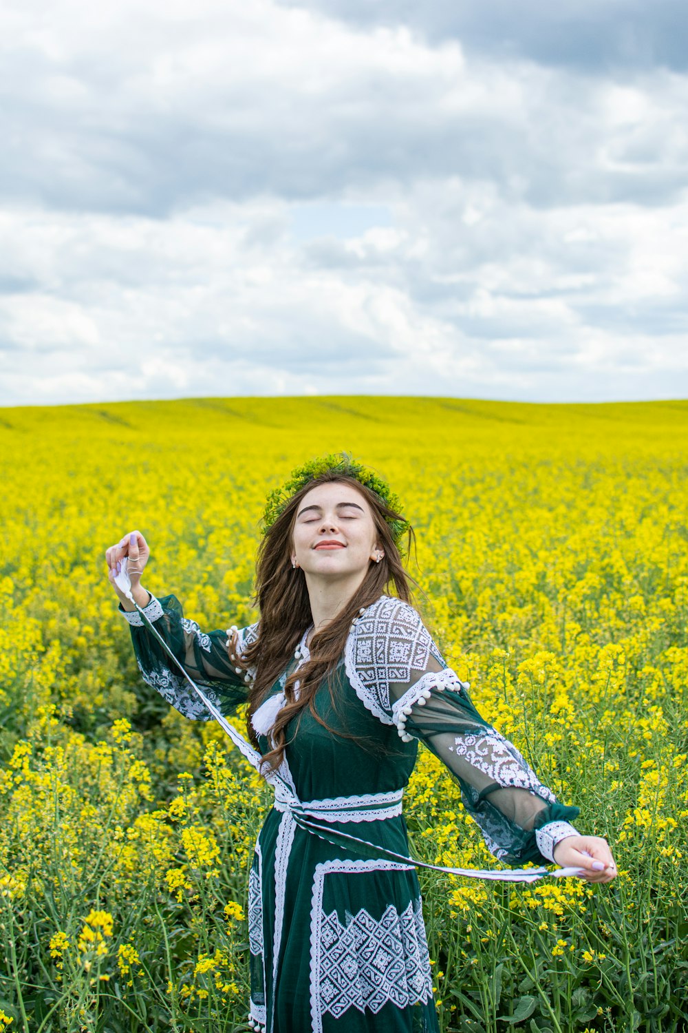 woman in blue and white checkered dress shirt standing on yellow flower field during daytime