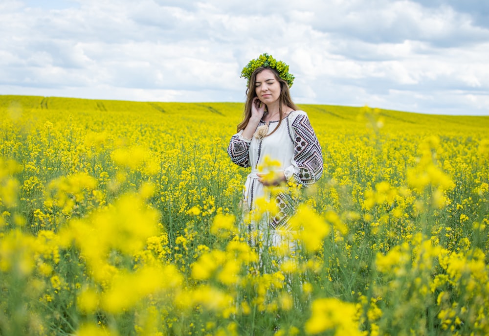 woman in white and black stripe long sleeve shirt standing on yellow flower field during daytime