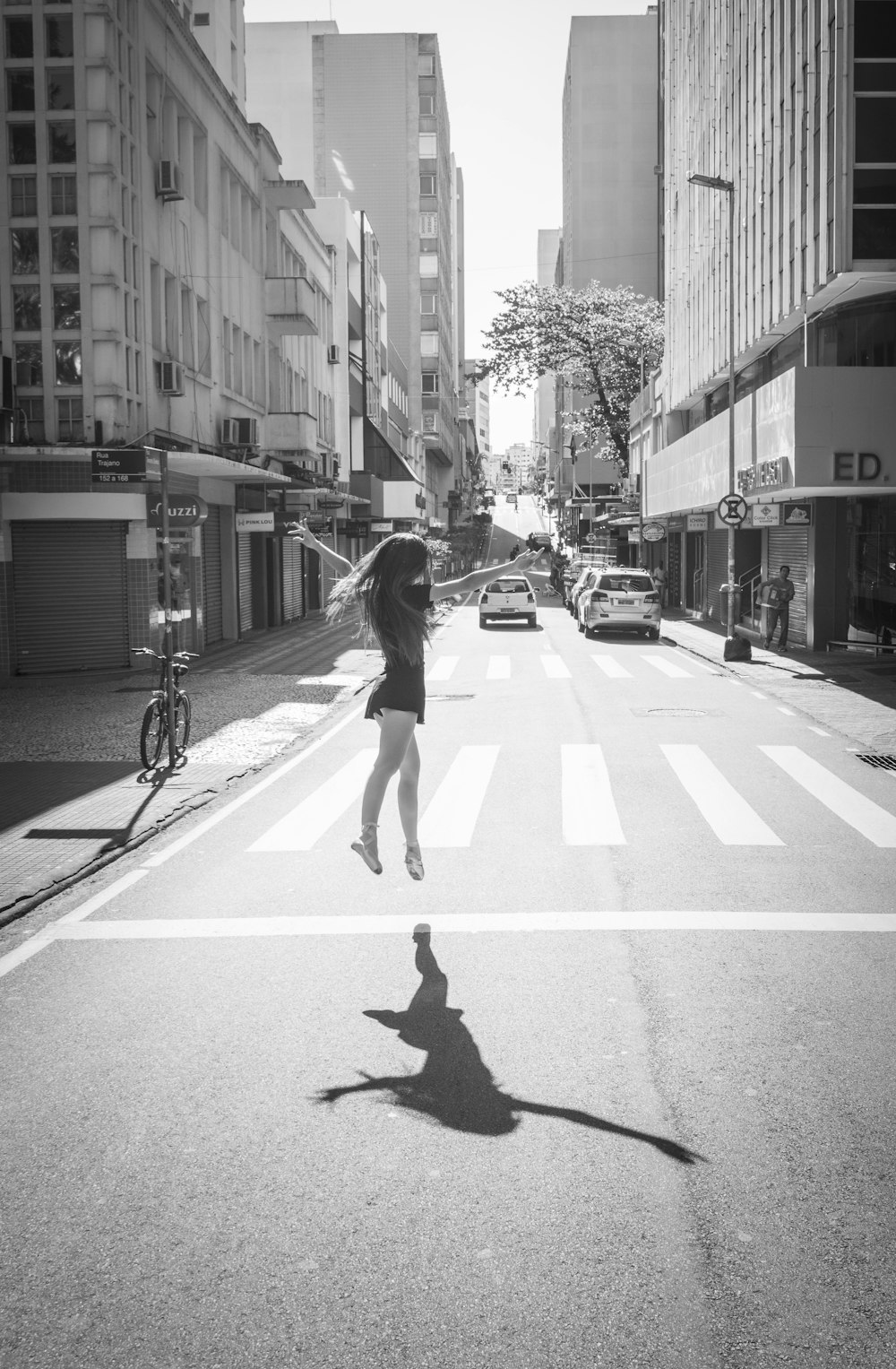 grayscale photo of woman walking on pedestrian lane