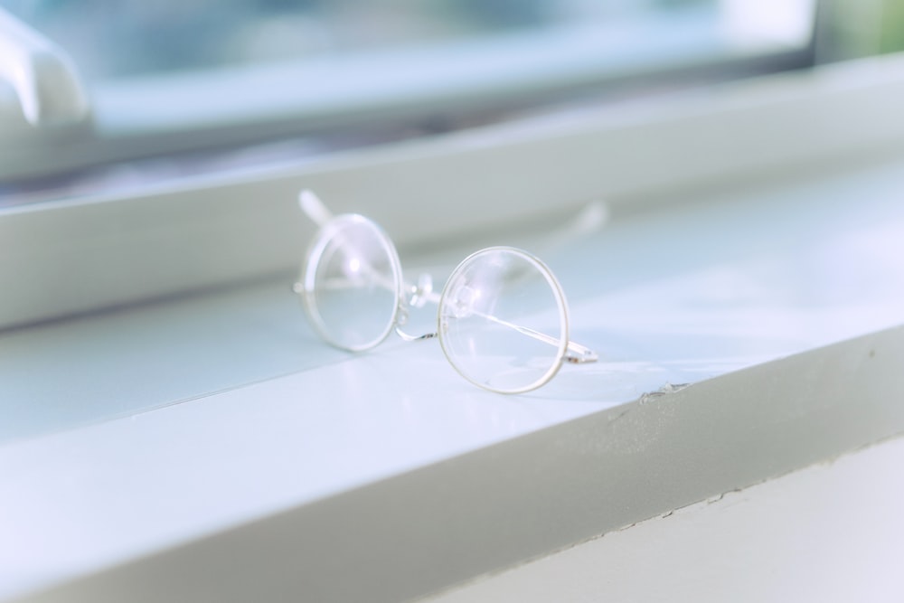 silver framed eyeglasses on white surface