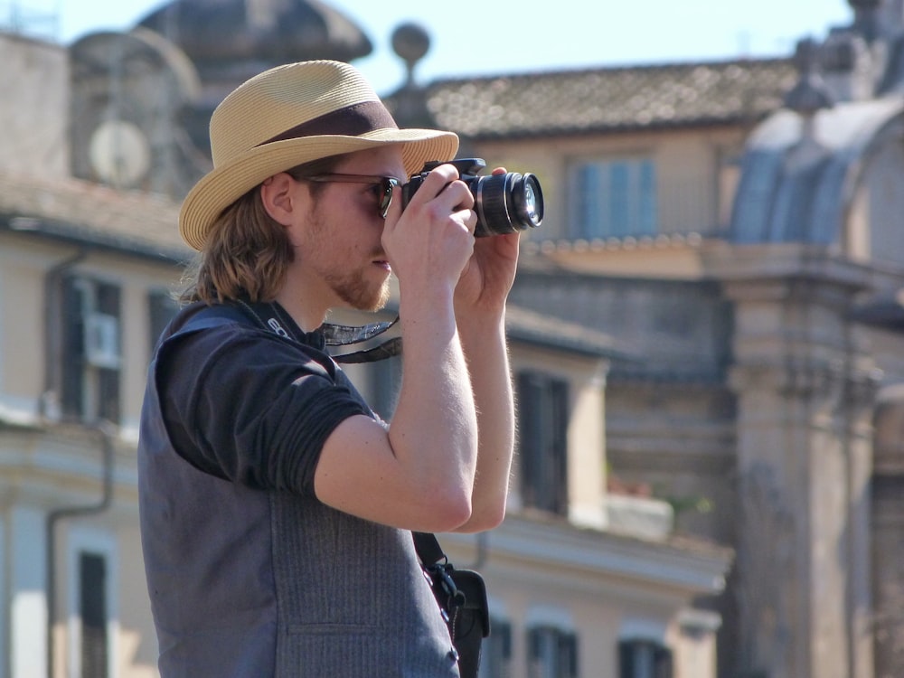 homme en t-shirt noir et chapeau fedora marron à l’aide de jumelles noires