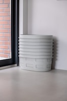 Stack of transparent plastic storage boxes with lids in a bright room