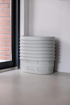 A cozy room corner featuring neatly stacked collapsible fabric storage bins in soft pastel colors.