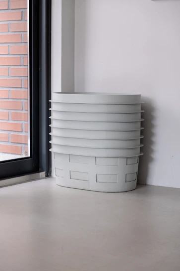 A cozy room corner featuring neatly stacked collapsible fabric storage bins in soft pastel colors.