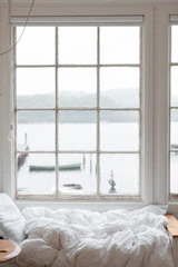 A window seat with cushions overlooking the tranquil waters of Dal Lake.