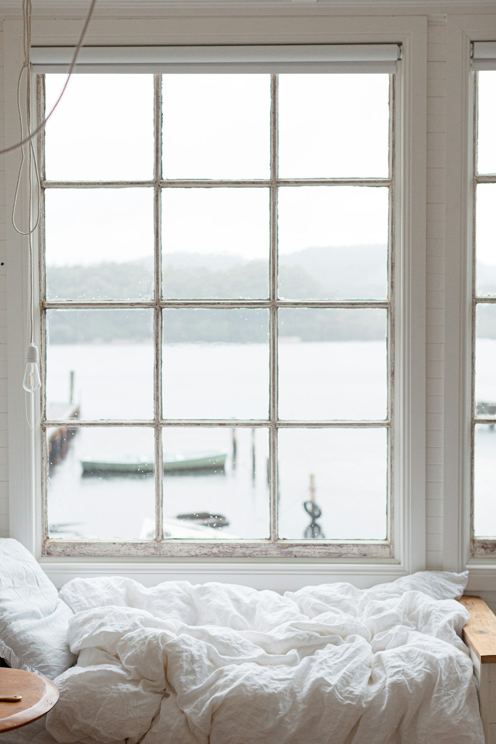 白いフレームのガラス窓の近くの白いベッドの写真 Unsplashで見つける屋内の無料写真