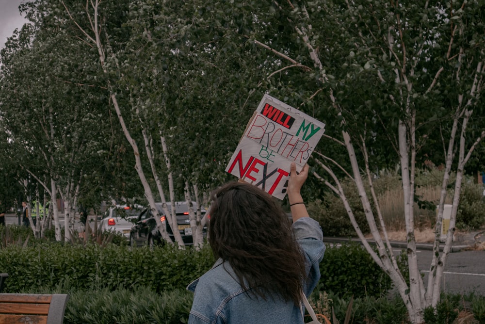 woman in blue shirt holding white and red signage