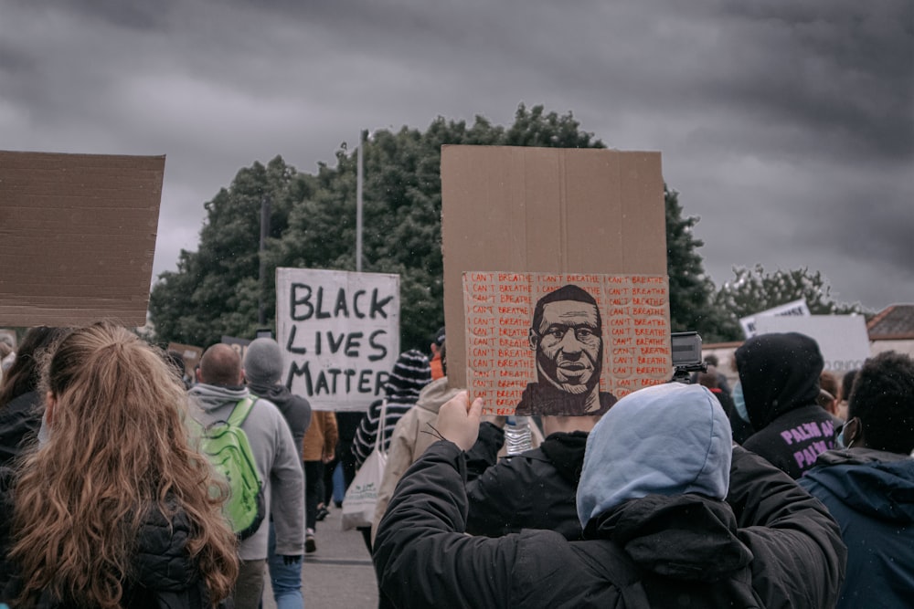 people holding white and black signage during daytime