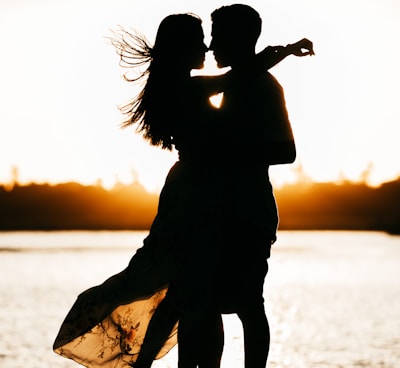 silhouette of woman standing on beach during sunset