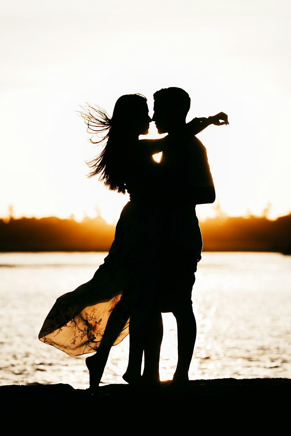 silhouette de femme debout sur la plage pendant le coucher du soleil