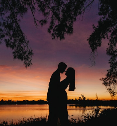 silhouette of man and woman kissing during sunset