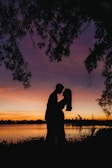 A serene sunset silhouette of Jona and Freya embracing by the lakeside.
