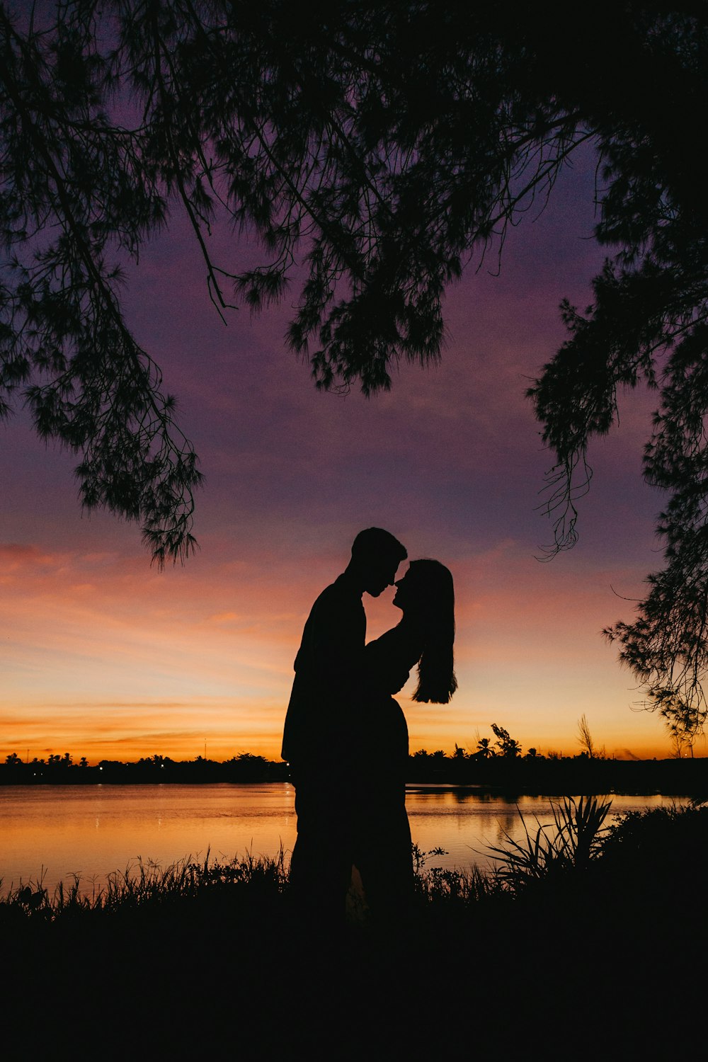 Silueta de hombre y mujer besándose durante la puesta del sol