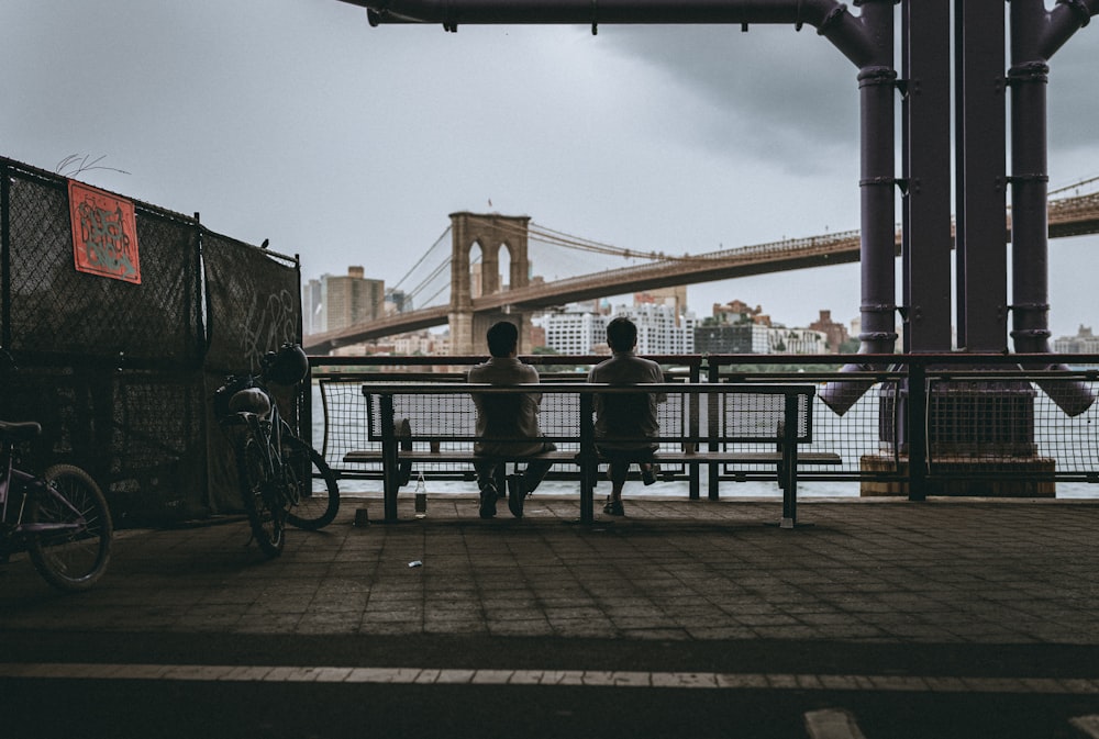 people sitting on bench near bridge during daytime