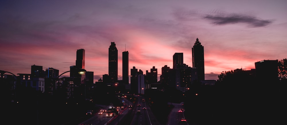 cars on road near city buildings during sunset