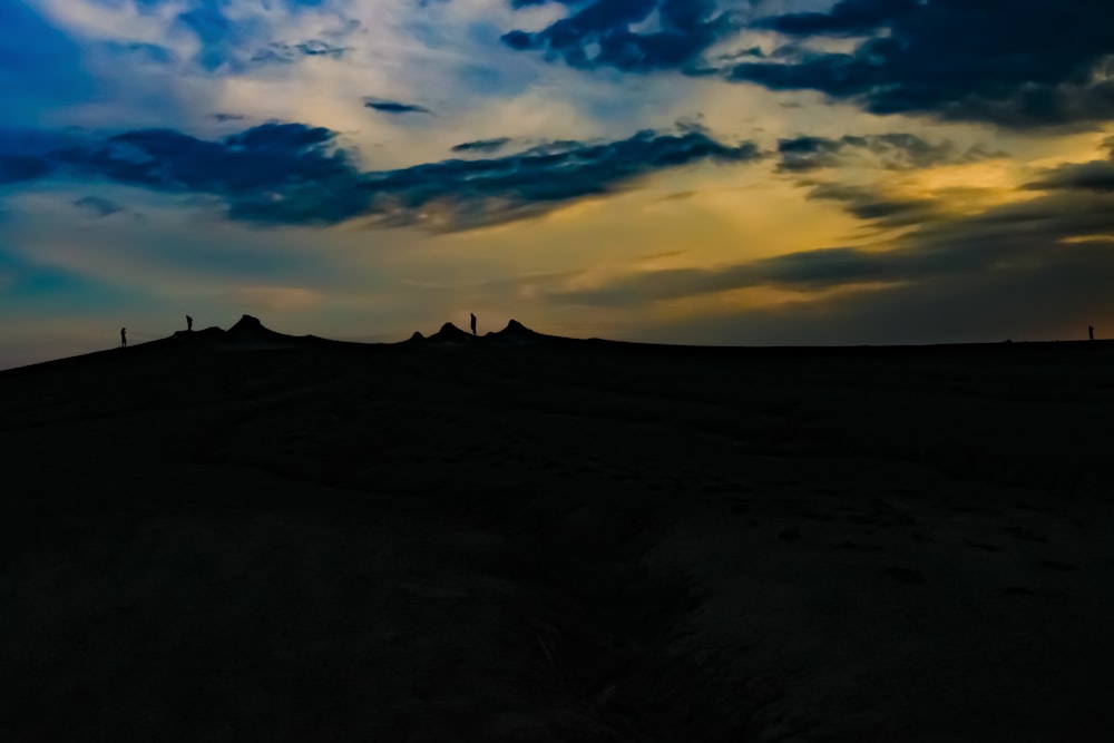 silhouette of mountain under cloudy sky during sunset