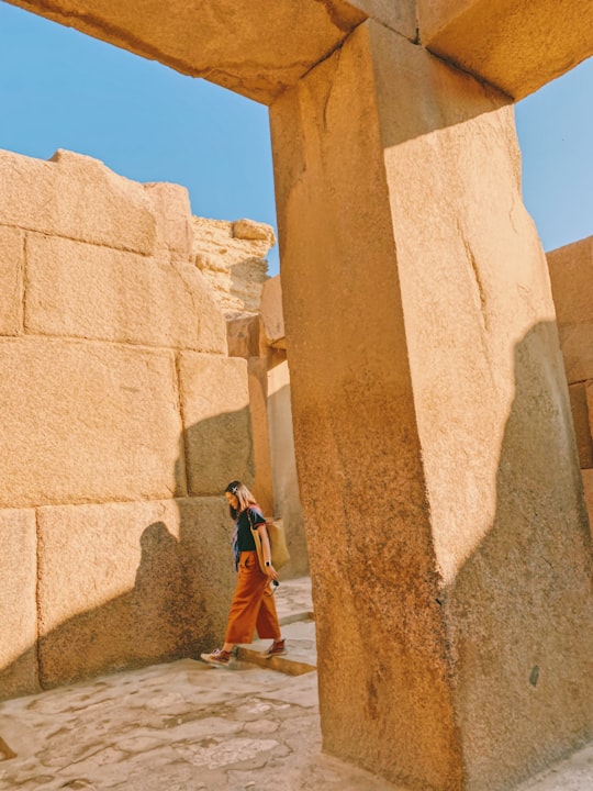 woman in brown coat standing near brown concrete wall during daytime in Saqqarah Egypt