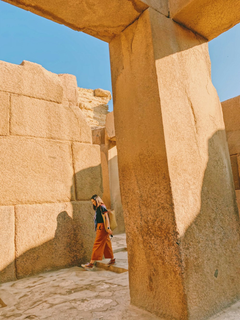 woman in brown coat standing near brown concrete wall during daytime