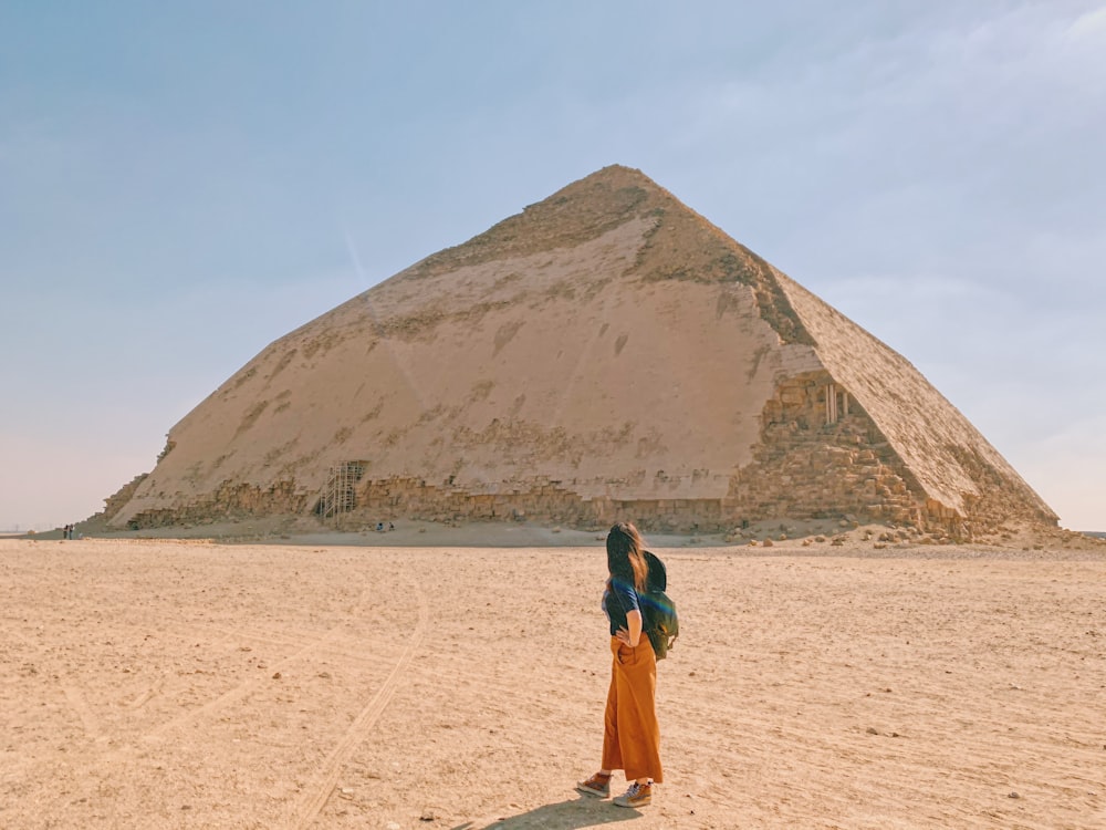 woman in blue jacket and brown skirt standing on white sand during daytime