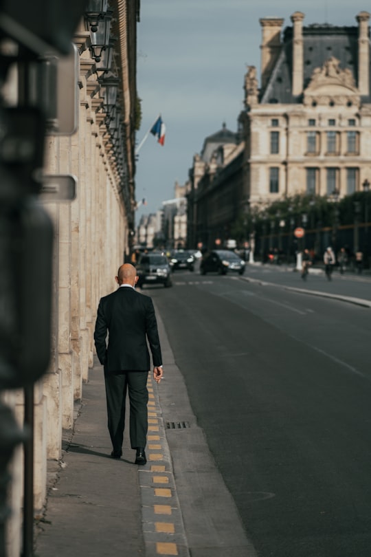 man in black coat standing on sidewalk during daytime in Rue de Rivoli France
