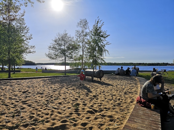 Family enjoying a sunny day at a lakeside park, children playing and parents smiling.