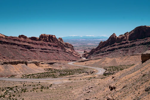 A winding desert trail leading through rugged terrain with distant mountains.