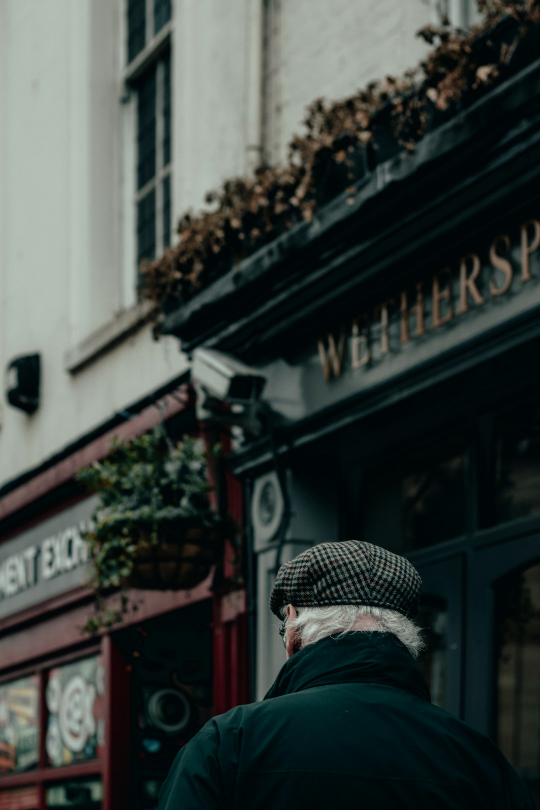 man in black and white plaid cap standing near building during daytime