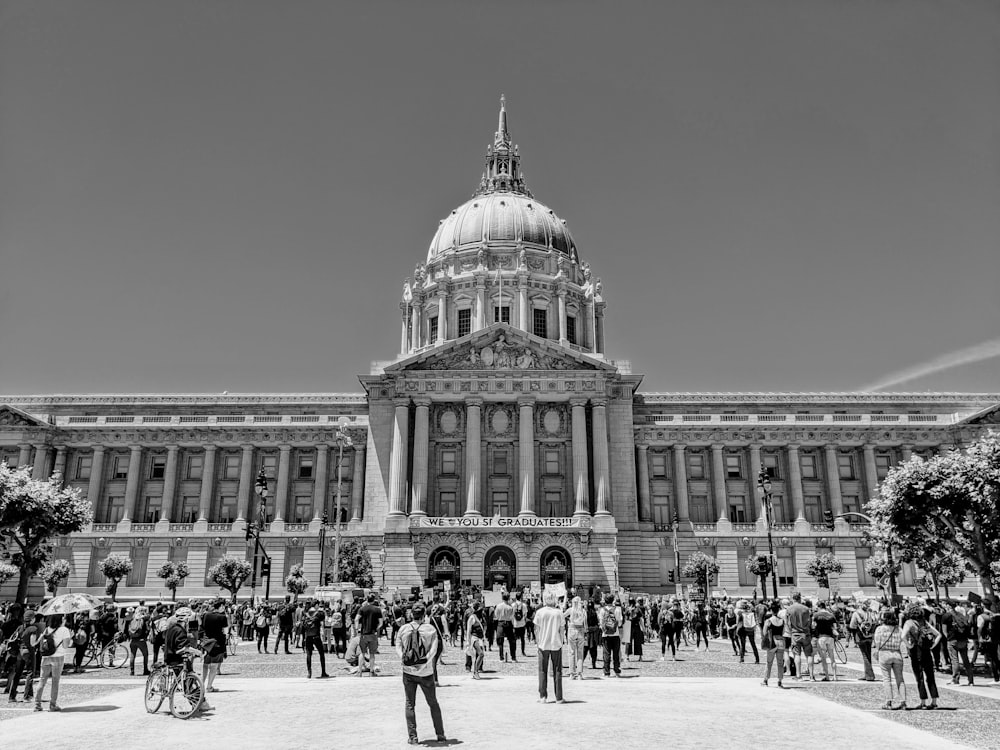 Foto en escala de grises de personas caminando cerca de un edificio