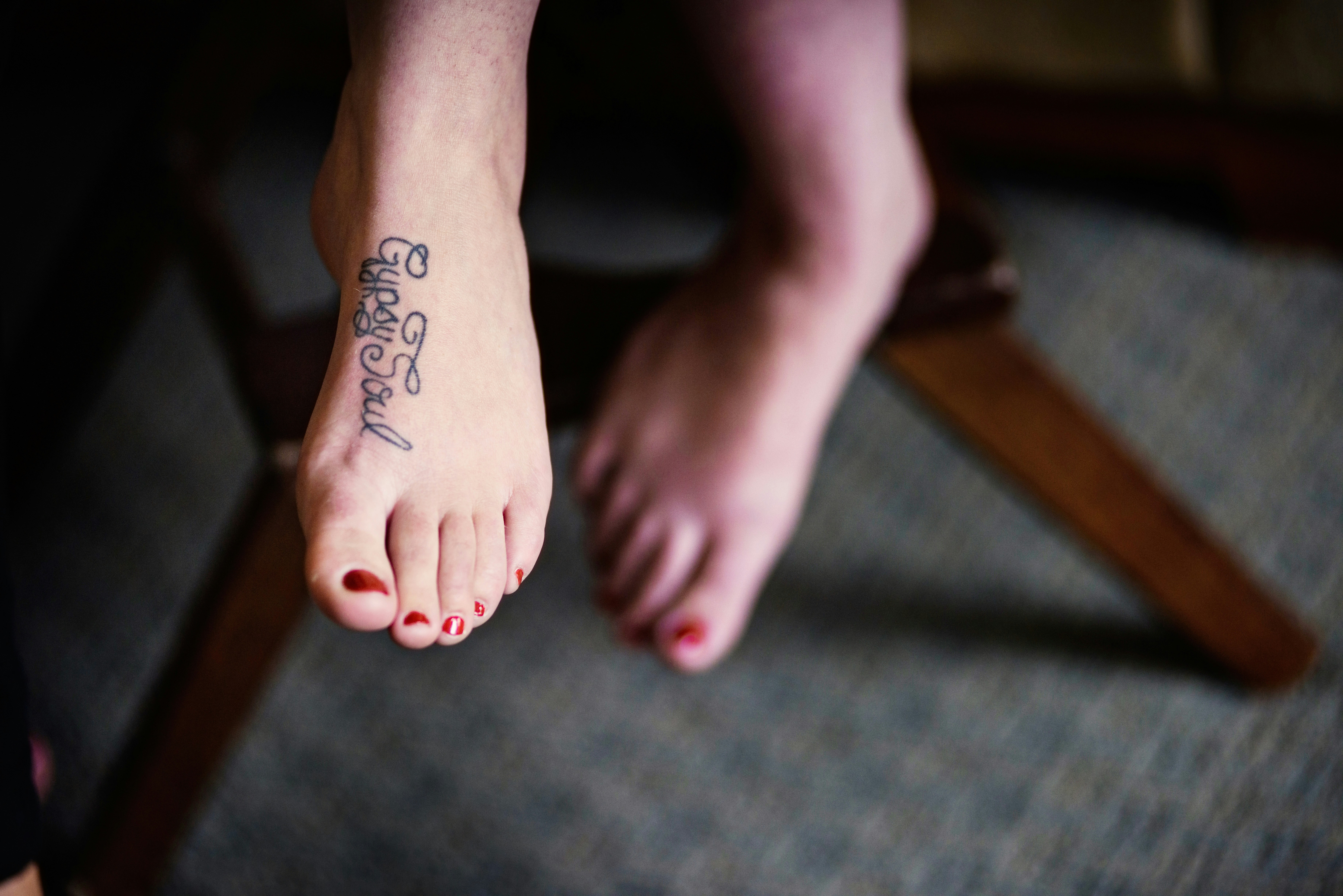 Gypsy Soul tattoo on bare feet with red-painted toenails.
