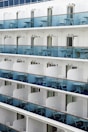 Close-up of a cruise ship balcony with chairs and railing.