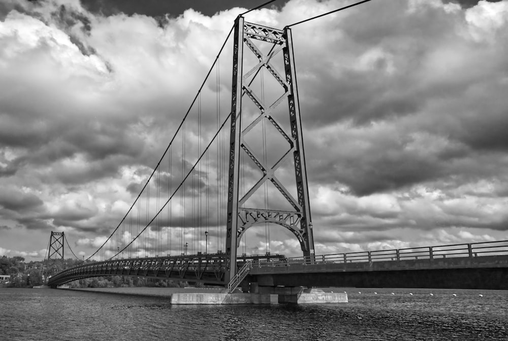 grayscale photo of bridge under cloudy sky