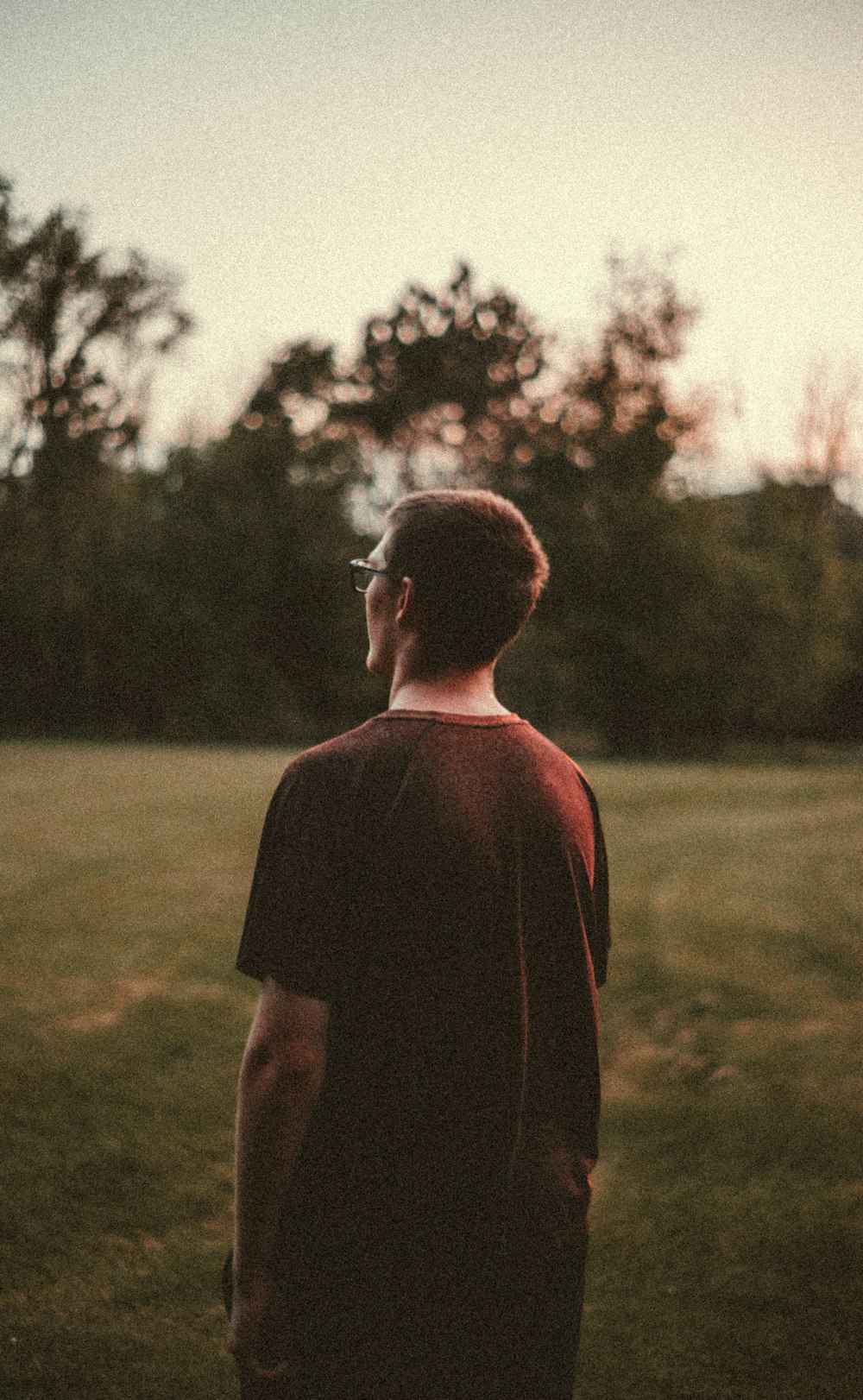 man in red shirt standing on green grass field during daytime