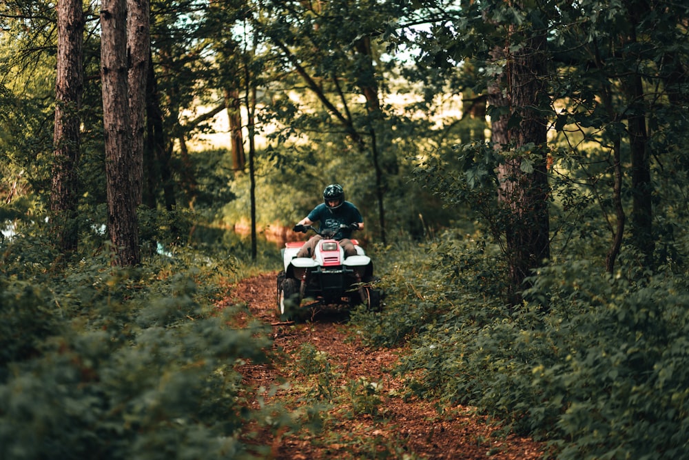 Hombre y mujer montando en motocicleta blanca y negra en el bosque durante el día